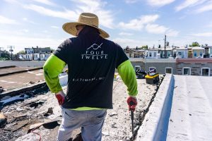 Four Twelve laborer looking over damaged flat roof